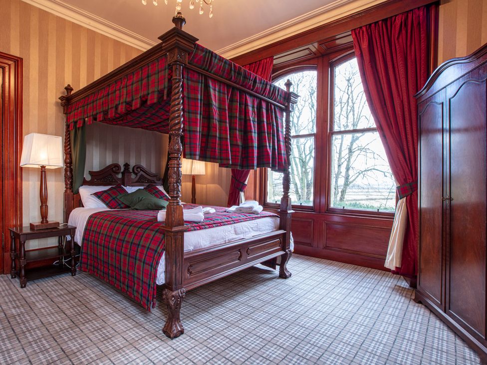 A bedroom with a four-poster bed and windows at Newton Manor House in Cupar
