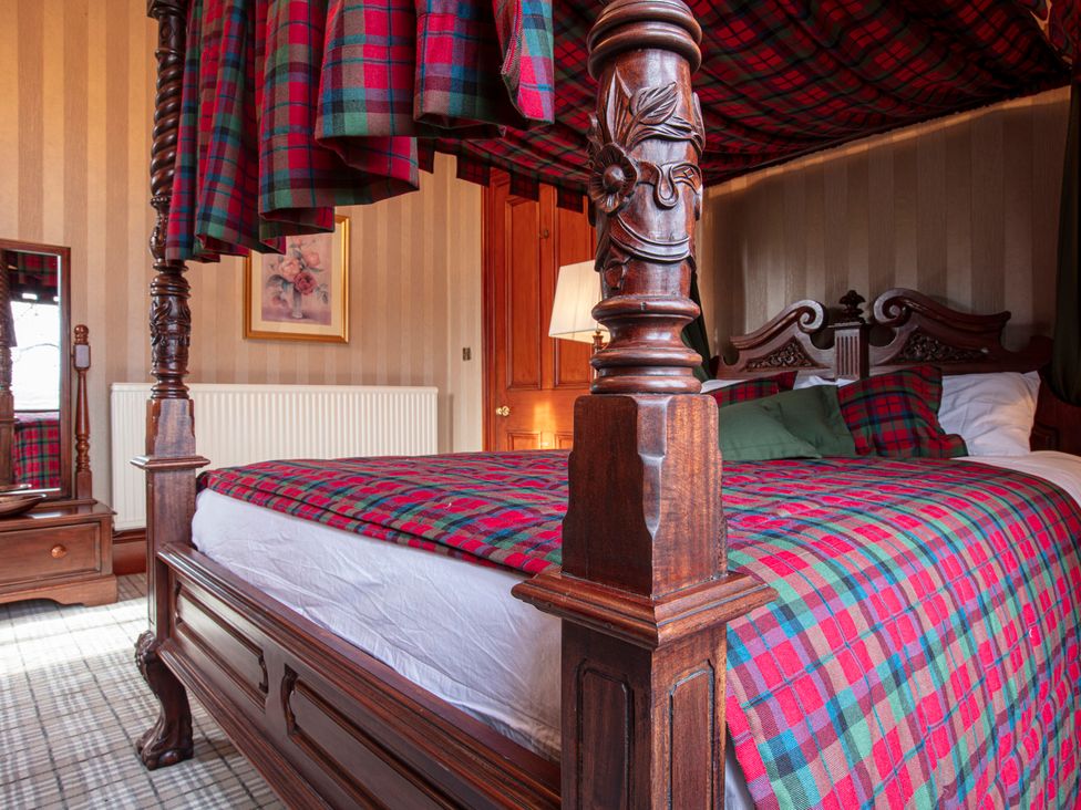 A bedroom with a four-poster bed and wooden furniture at Newton Manor House in Cupar