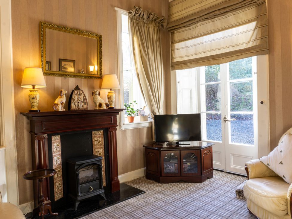 A living room with a fireplace and television at Newton Manor House in Cupar