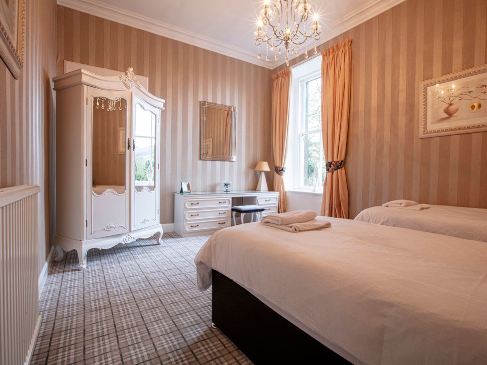 A bedroom with two beds and a wardrobe at Newton Manor House in Cupar