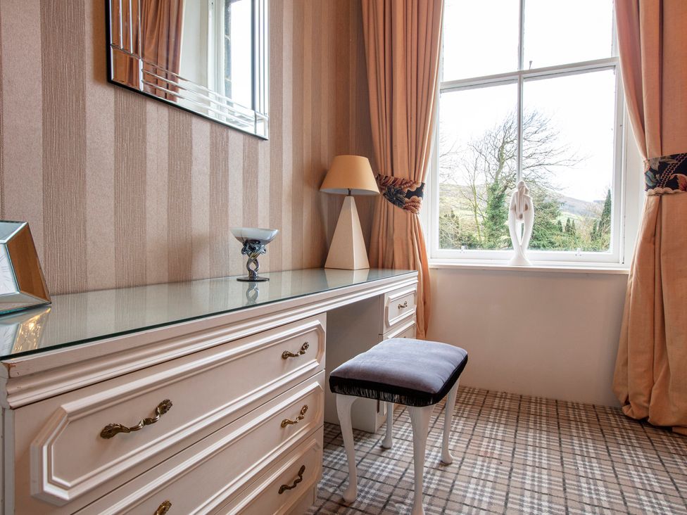 A dresser with a lamp and chair in a bedroom at Newton Manor House Cupar