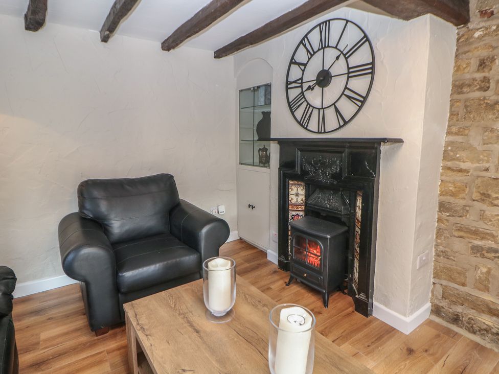A living room with a clock and a fireplace at Lake Side Cottage in Wakefield