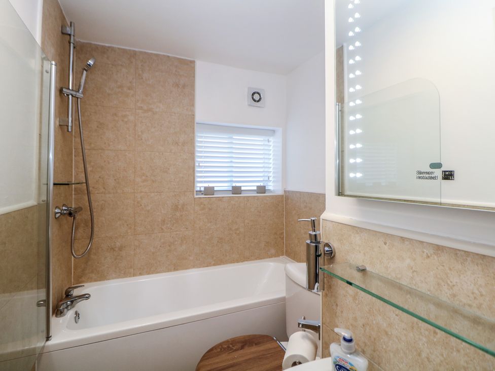 A bathroom featuring a bathtub, shower, and sink at Lake Side Cottage in Wakefield