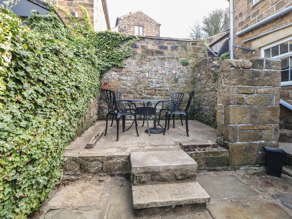 A garden with a stone wall and a table and chairs at Lake Side Cottage in Wakefield