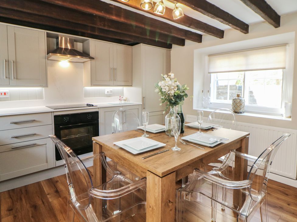A kitchen with a wooden table and clear chairs at Lake Side Cottage in Wakefield