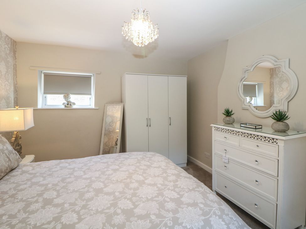 A bedroom with a bed, wardrobe, and dresser at Lake Side Cottage in Wakefield