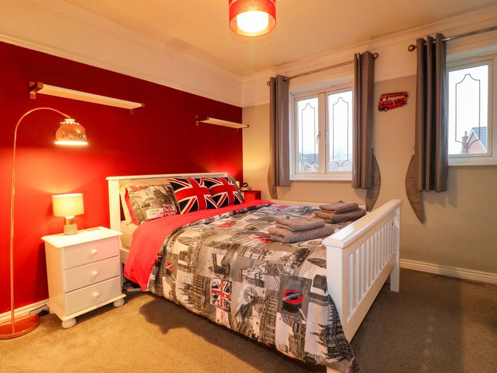 A bedroom with a bed, bedside table, and curtain at 41 Lower Birches Way, Rugeley