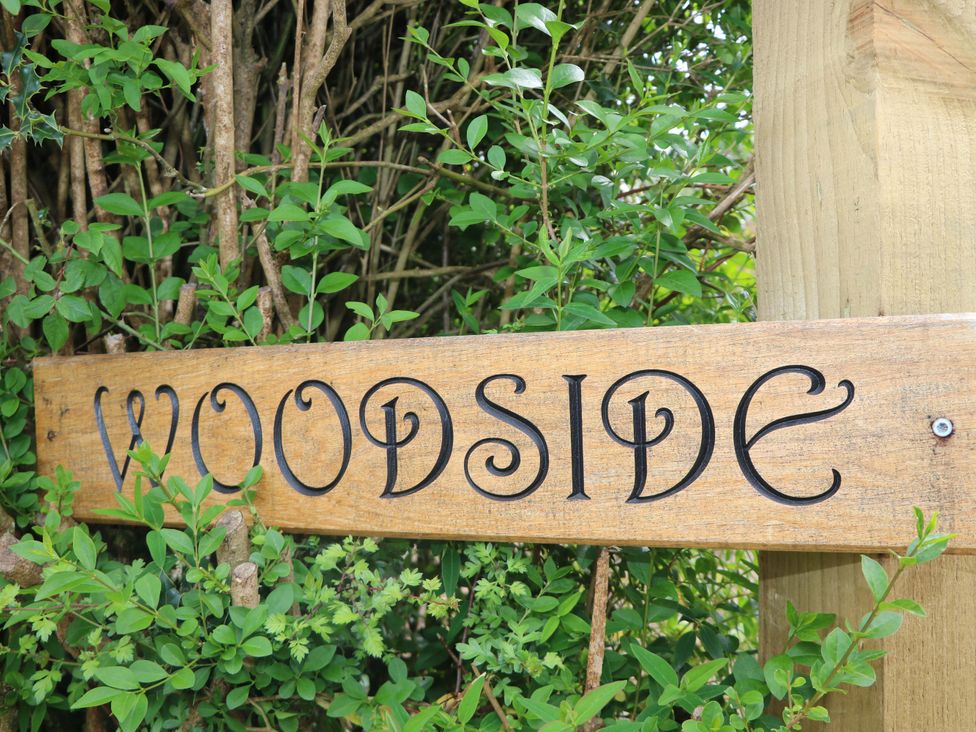 A wooden sign reading Woodside surrounded by greenery at Woodside in Battle