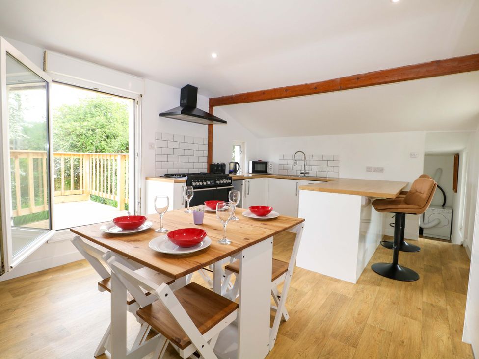 A dining area with a table and kitchen appliances at Woodside in Battle