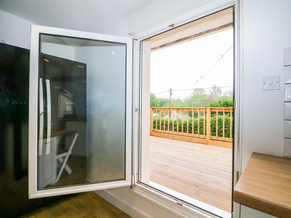 A kitchen with a fridge and a door leading to the deck at Woodside in Battle
