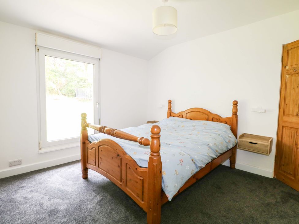 A bedroom with a wooden bed and window at Woodside in Battle