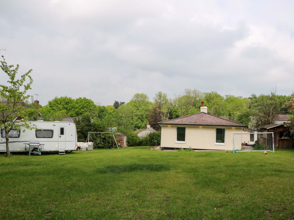 A house with a caravan and swing set in the garden at Woodside in Battle