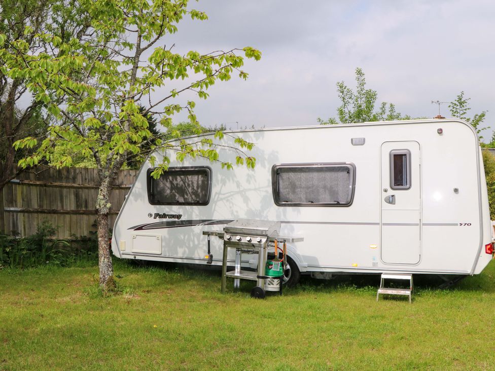 A caravan with a grill and tree in a grassy area at Woodside in Battle