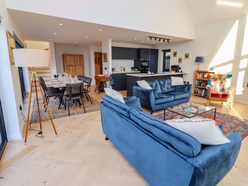 A living room with a sofa, dining table, and kitchen at 1 Dairy Fields Longframlington