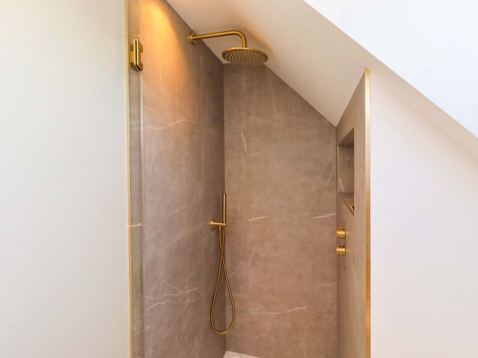 A shower with a golden showerhead and faucet at 1 Dairy Fields in Longframlington