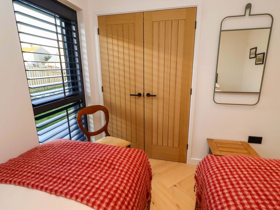 A bedroom with two beds and wooden doors at 1 Dairy Fields Longframlington