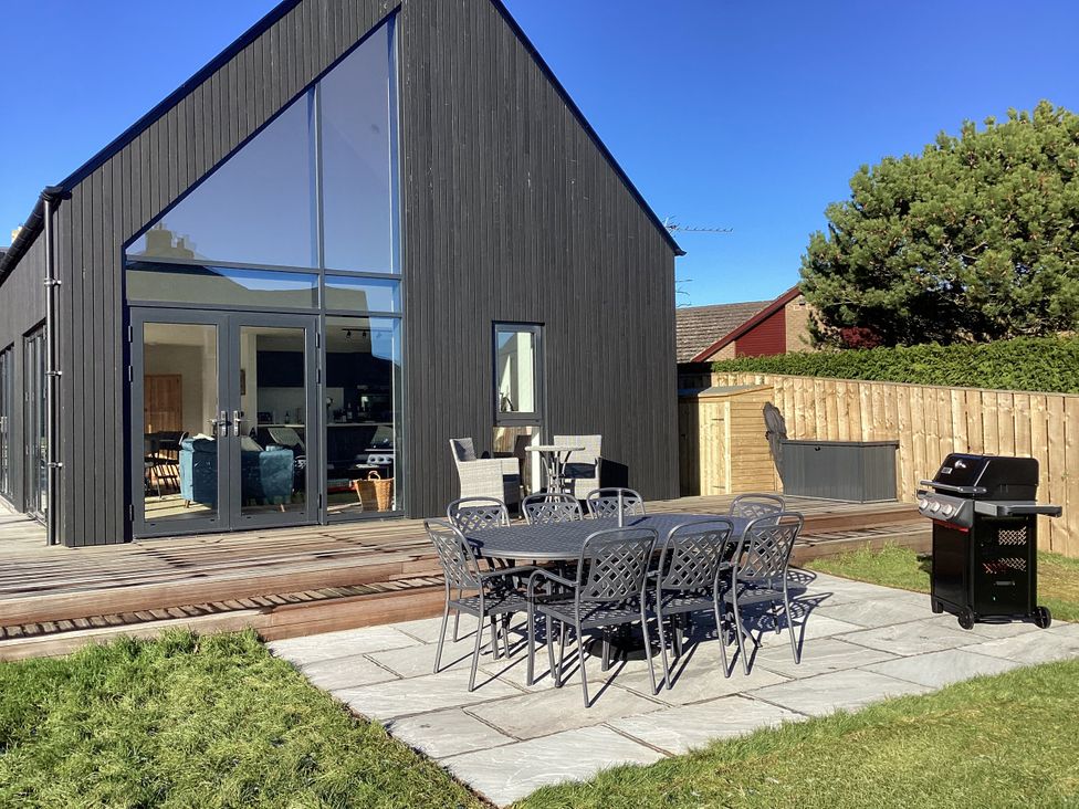 A house with an outdoor table and chairs in a garden at The Barn in Longframlington