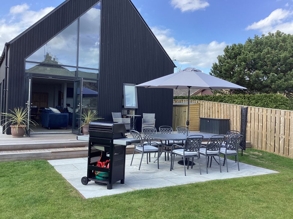 An outdoor seating area with a barbecue grill and table at The Barn in Longframlington