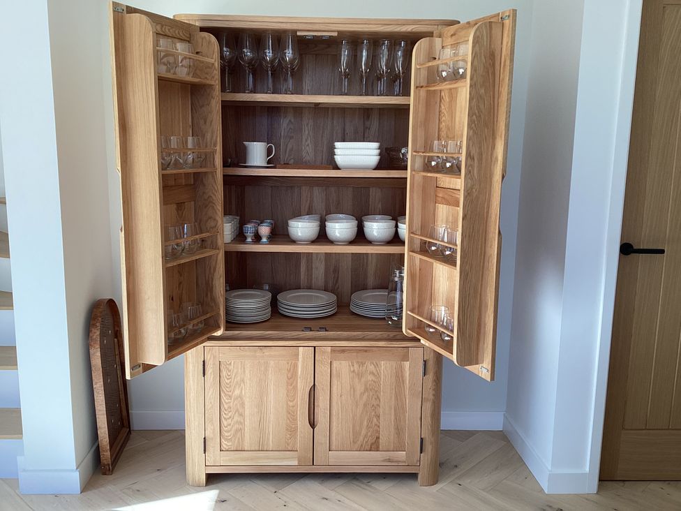 A wooden cupboard with glassware and dishes at The Barn in Longframlington