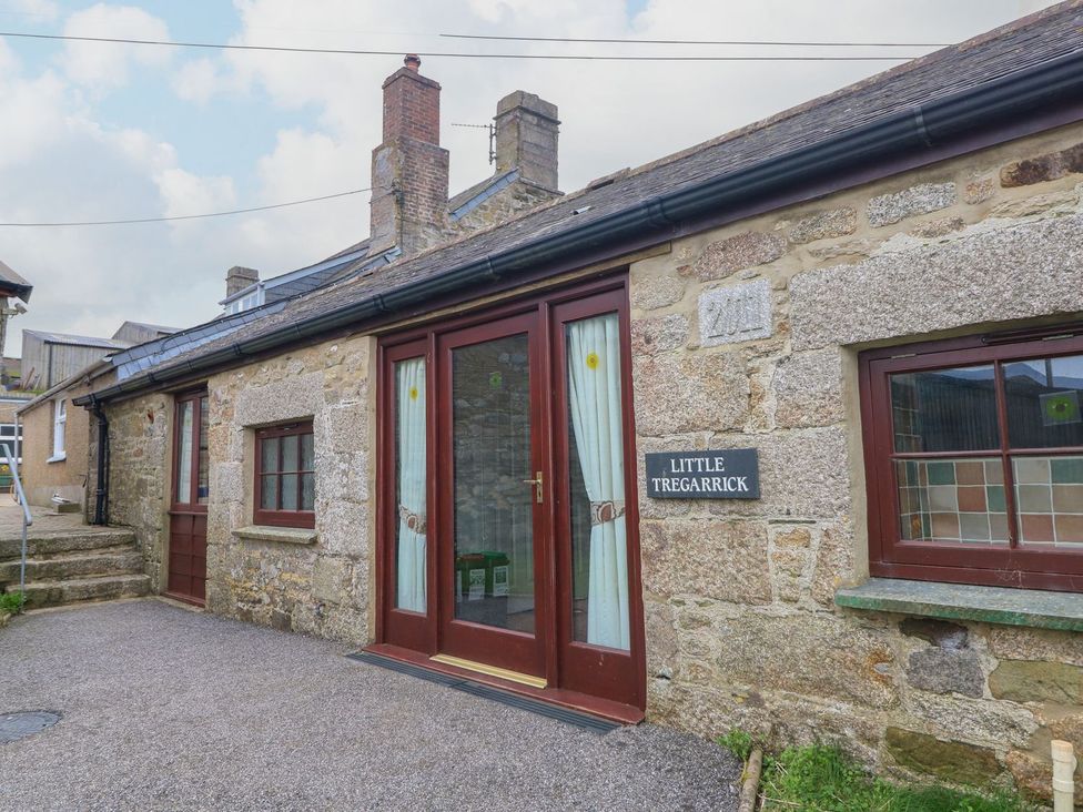An exterior view of a stone building with a door and windows at Little Tregarrick in Helston