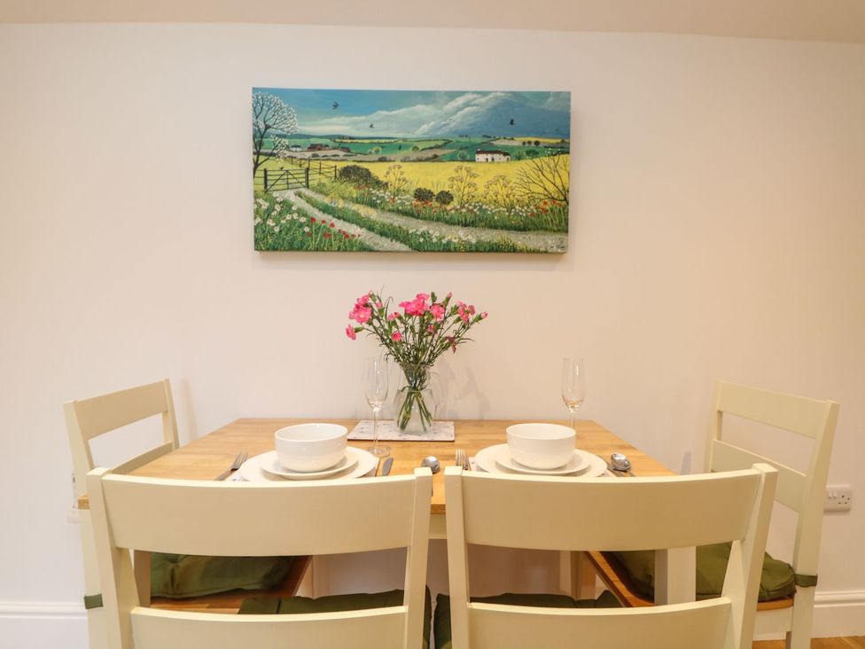 A dining room with a wooden table set for two at Little Tregarrick in Helston