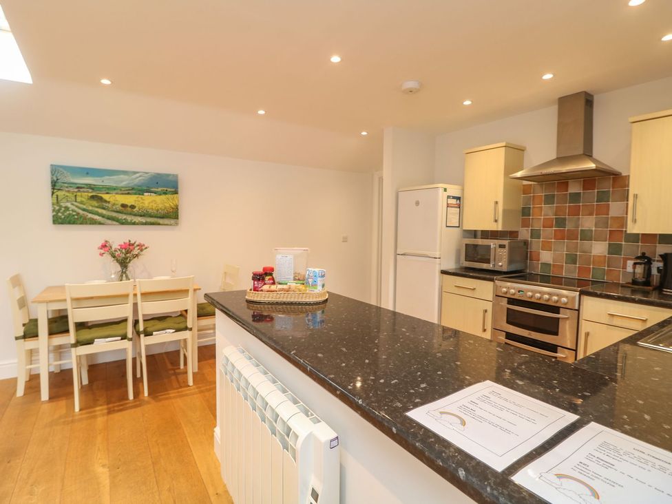 A kitchen with appliances and dining area at Little Tregarrick in Helston