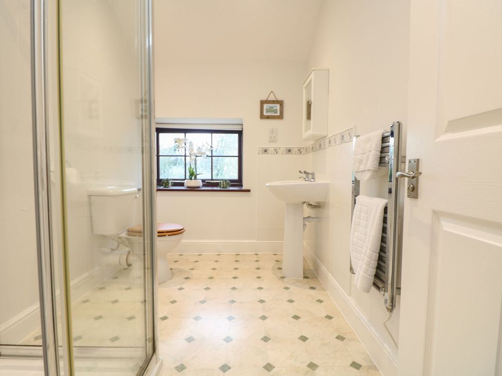 A bathroom with a shower, toilet, and sink at Little Tregarrick in Helston