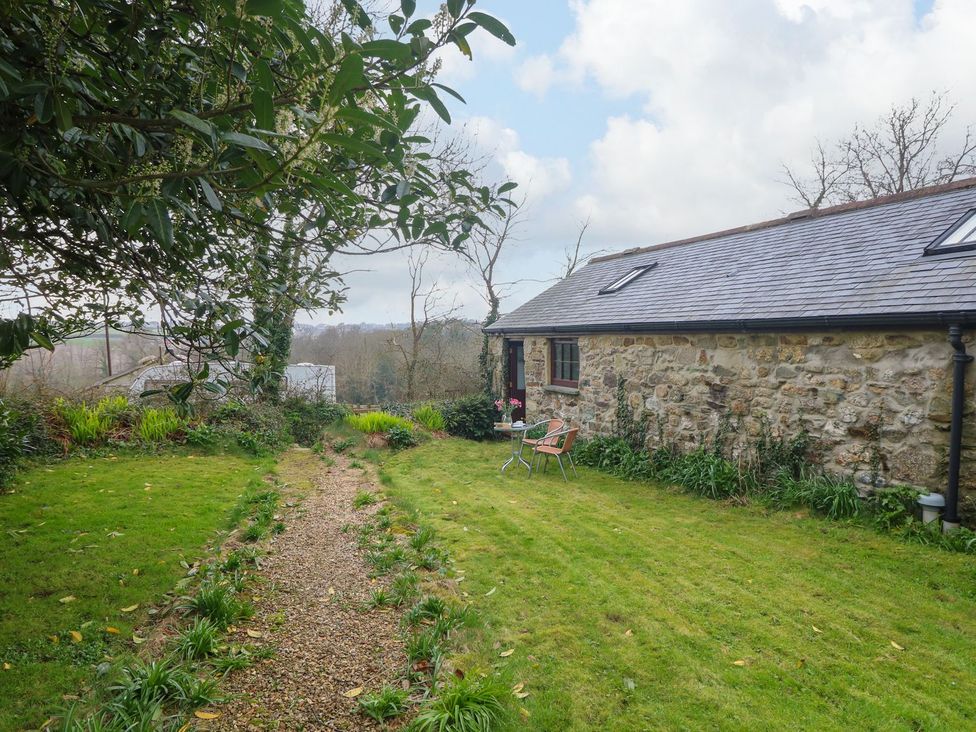A garden with a gravel path and seating area at Little Tregarrick in Helston