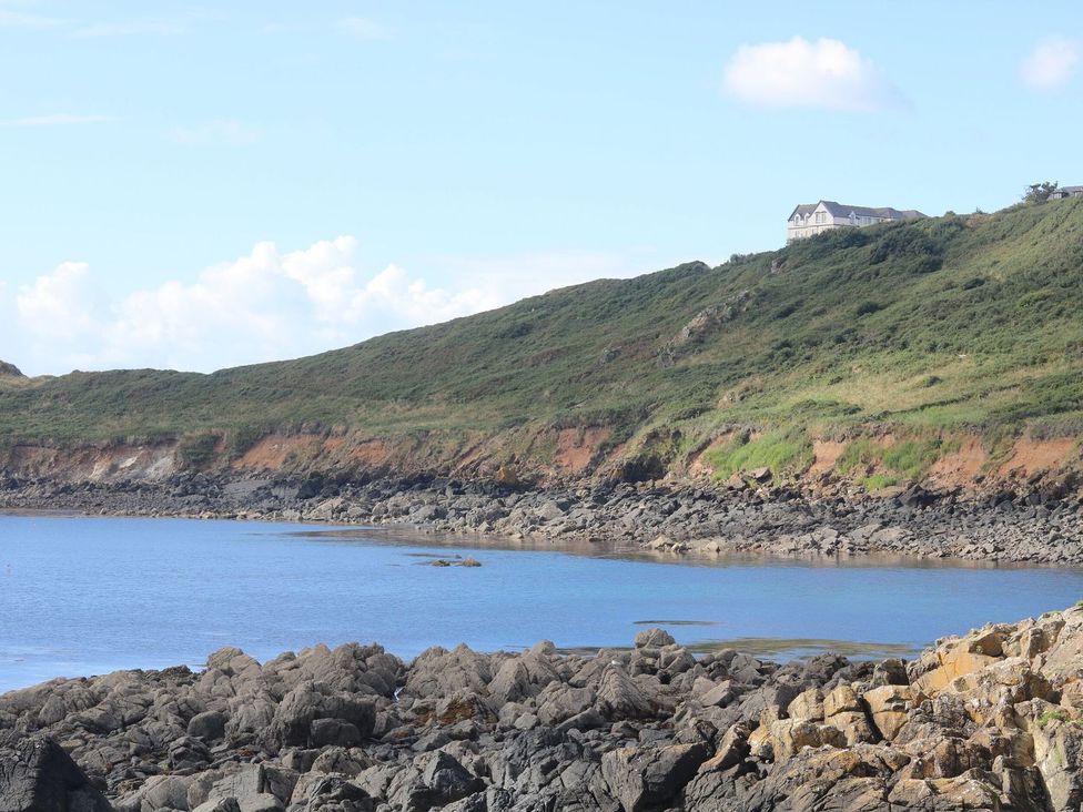 A house on a hill overlooking rocks and water at Little Tregarrick in Helston