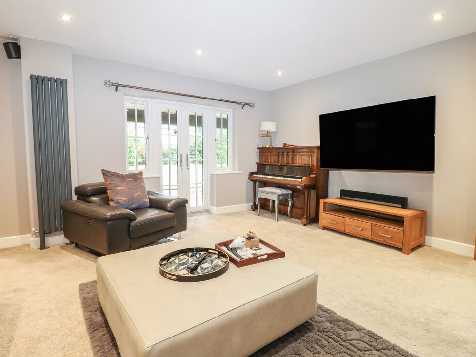 A living room with a piano and television at Woodlands house in Ringwood