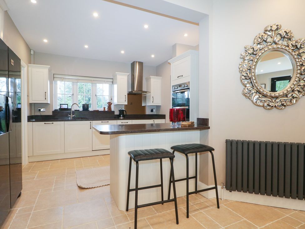 A kitchen with modern appliances and bar stools at Woodlands house in Ringwood