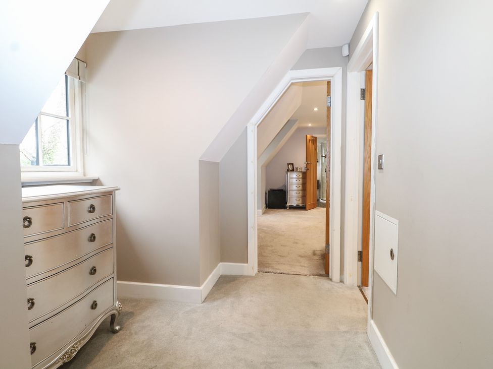 A hallway with a chest of drawers and doors at Woodlands house in Ringwood