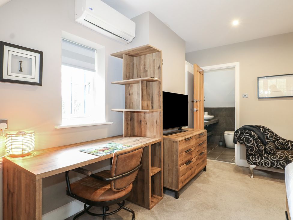 A bedroom with a desk and television at Woodlands house Ringwood