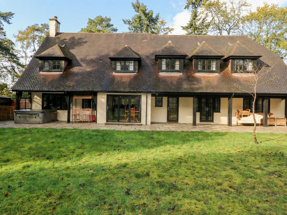 An outdoor area with a house and a hot tub at Woodlands house in Ringwood
