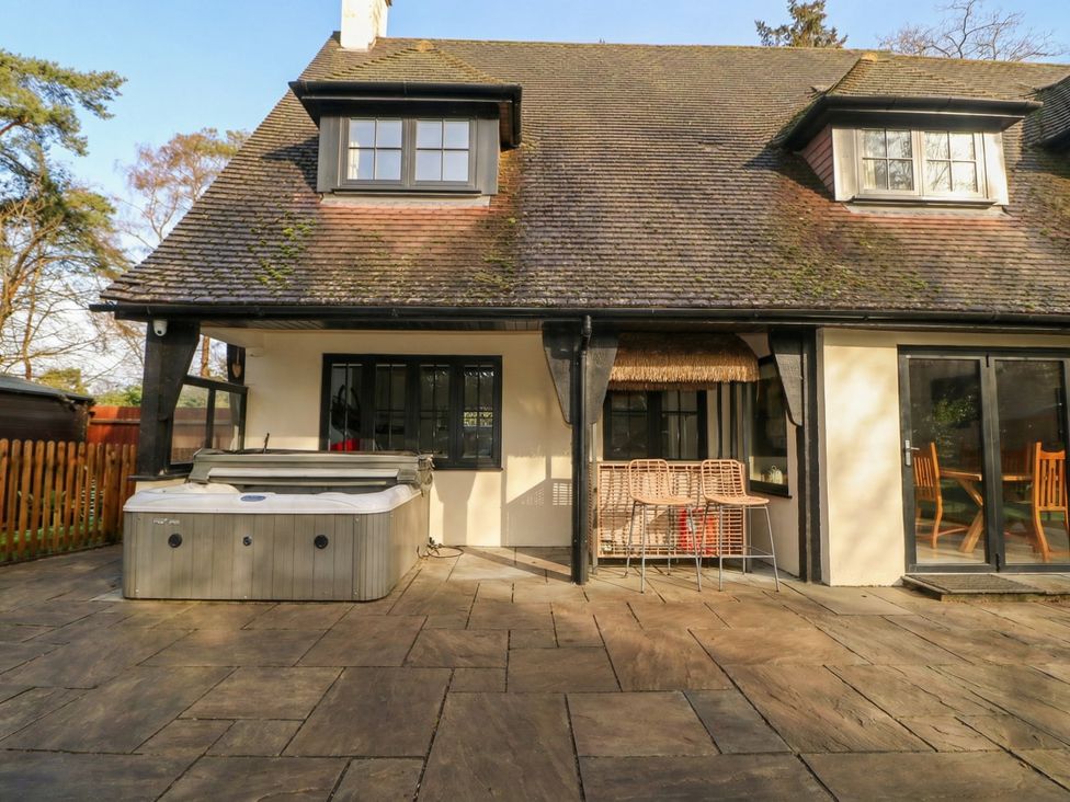 An outdoor patio with a hot tub and bar stools at Woodlands house Ringwood