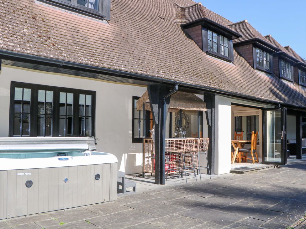 An outdoor area with a hot tub and seating at Woodlands House in Ringwood