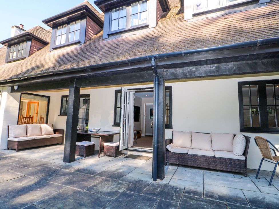 An outdoor patio with seating and a table at Woodlands House Ringwood