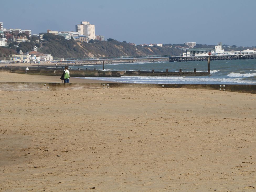 A beach with a person walking near the water at Woodlands House in Ringwood