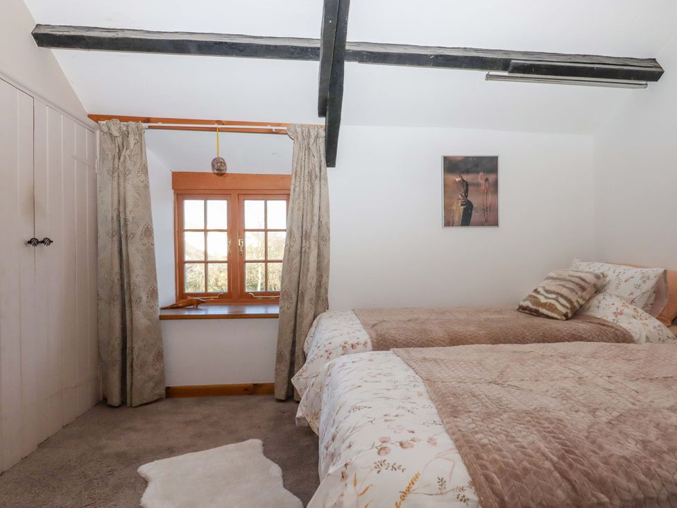 A bedroom with two beds and a window at Park Cottage in Kingsbridge