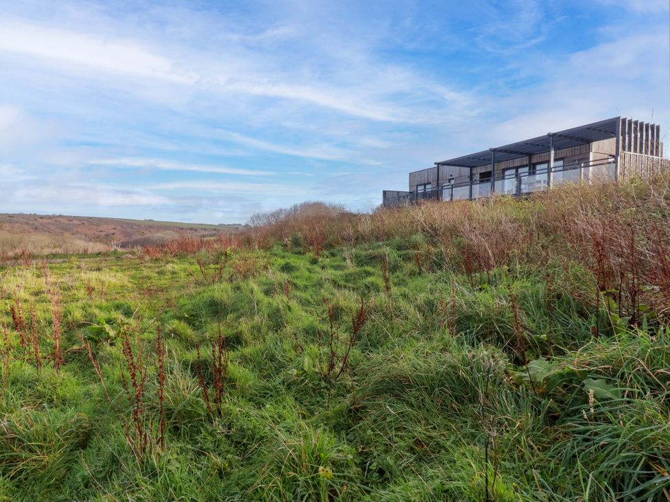 A building in a grassy area under a cloudy sky at 114 - The Residance in Redruth