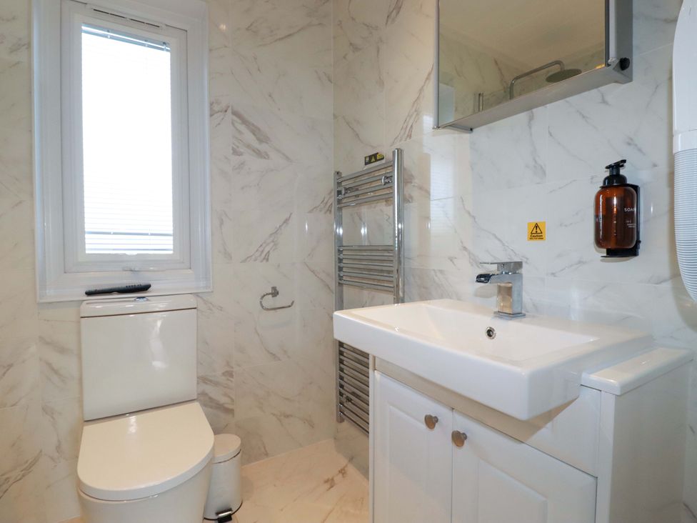 A bathroom with a toilet, sink, and mirror at 114 - The Residance in Redruth