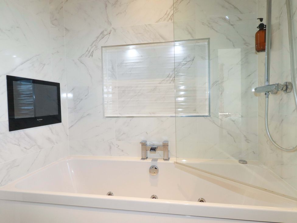 A bathtub with a showerhead and wall-mounted television at 114 - The Residance in Redruth