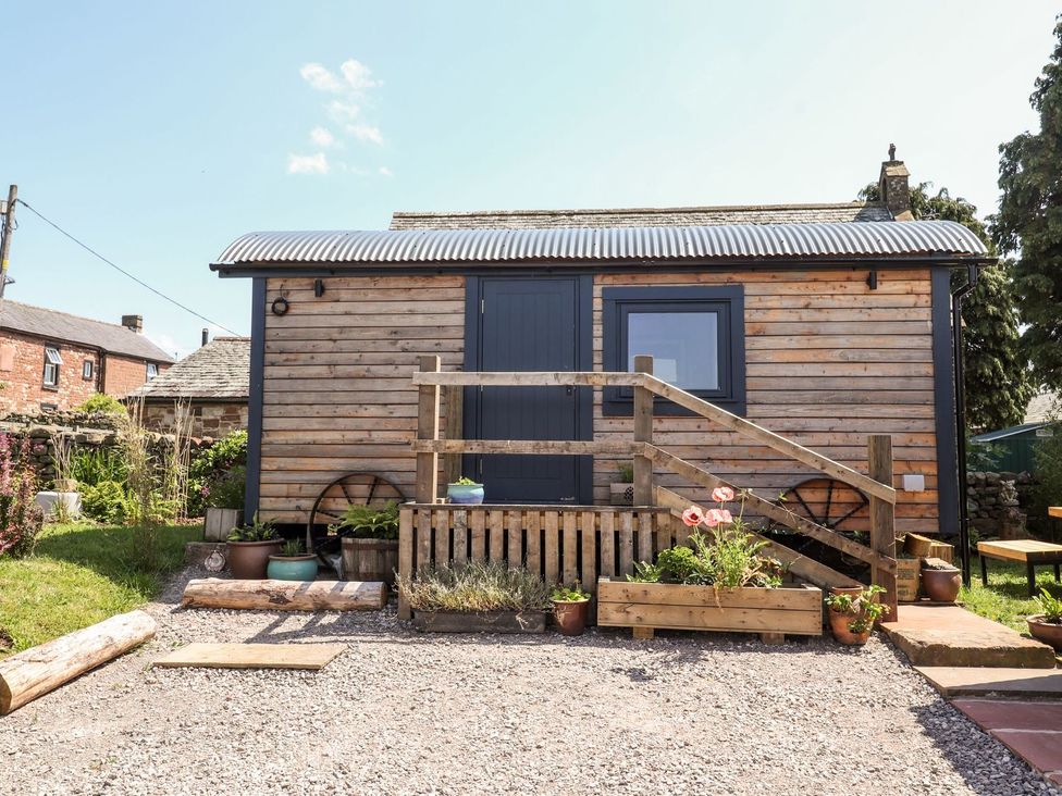 A wooden shepherd's hut with steps and plants at Dunfell Shepherd's Hut in Appleby-In-Westmorland