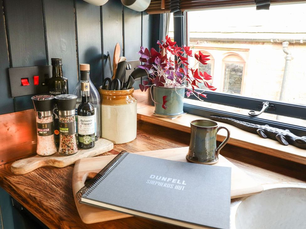 A kitchen counter with spices and a notebook at Dunfell Shepherd's Hut in Appleby-In-Westmorland