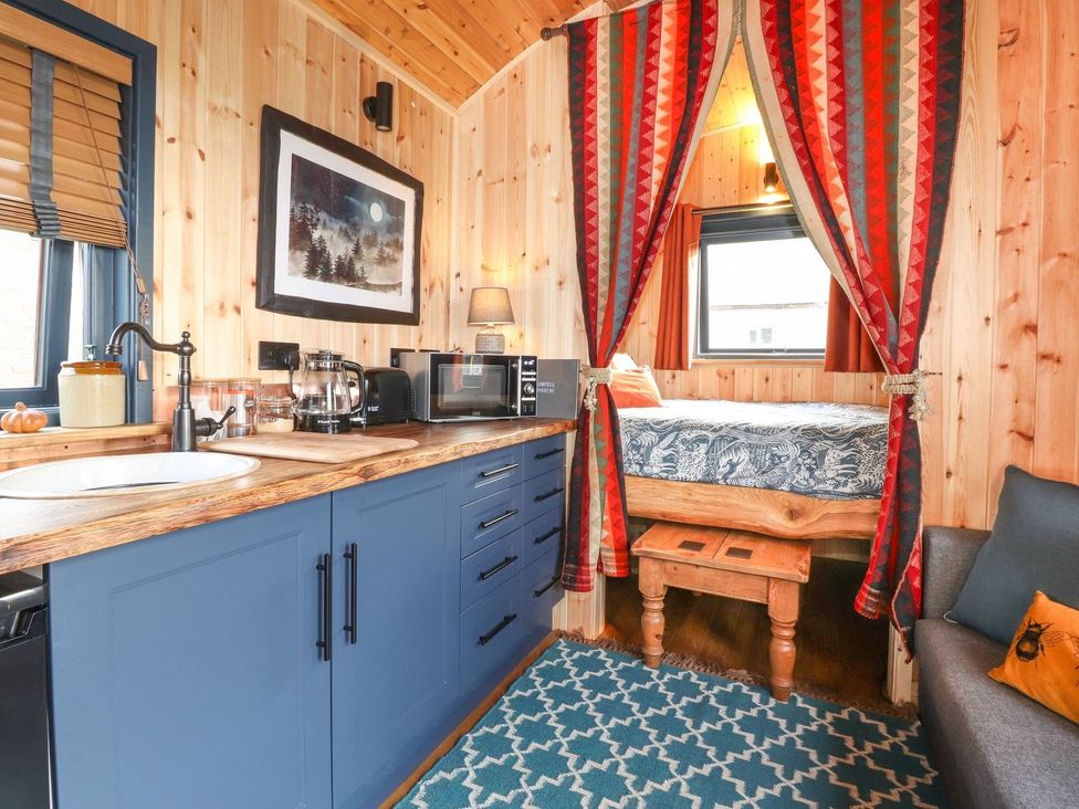 A living room with a kitchen area and bed at Dunfell Shepherd's Hut in Appleby-In-Westmorland