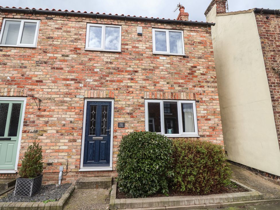 A house exterior with a blue front door and windows at Mallard Cottage in Nafferton