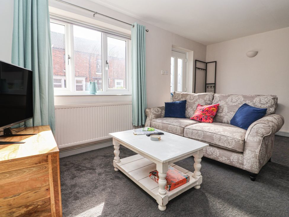 A living room with a sofa and television at Mallard Cottage Nafferton