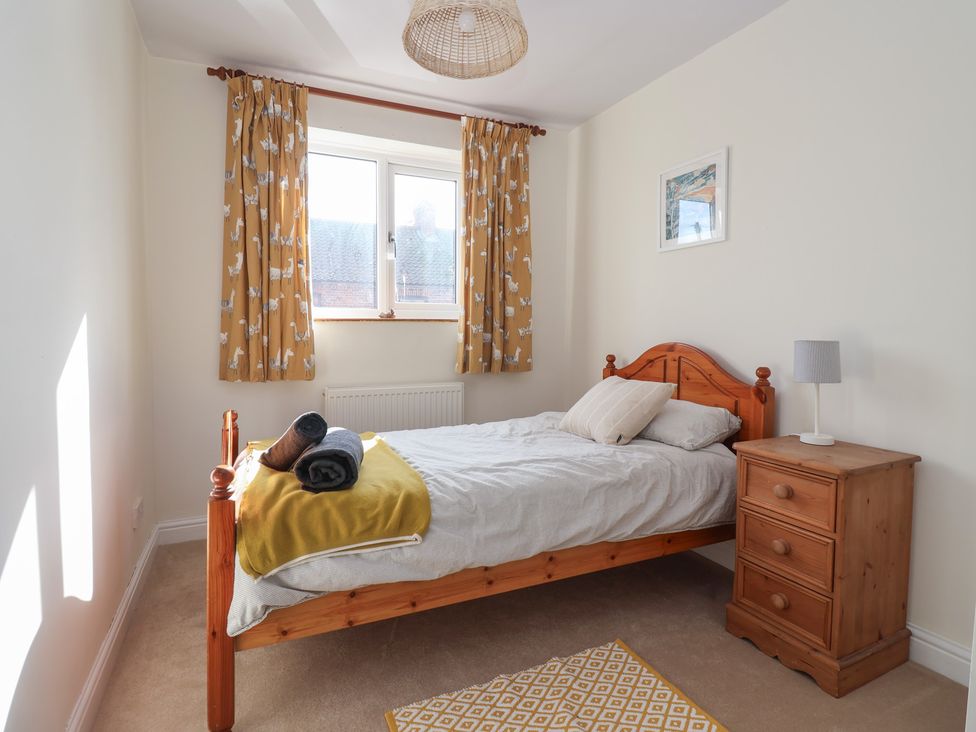 A bedroom with a wooden bed and bedside table at Mallard Cottage in Nafferton
