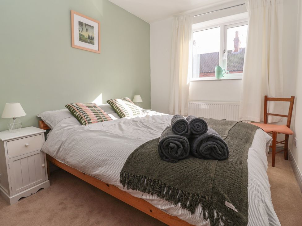 A bedroom with a bed, towels, and a window at Mallard Cottage Nafferton