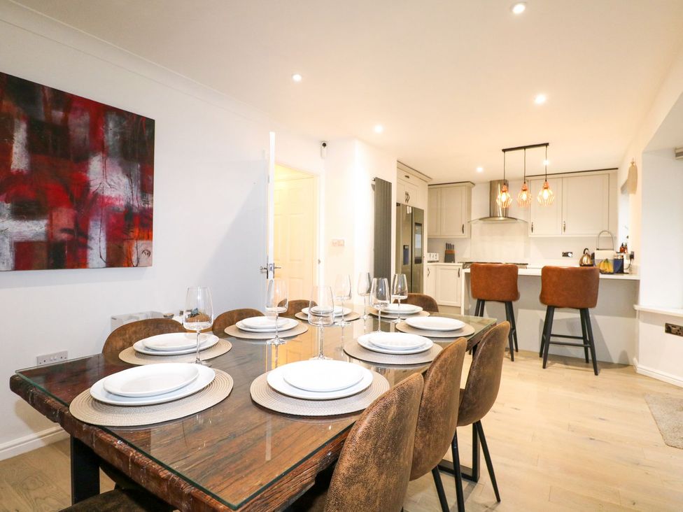 A dining room with a table set for dinner and a kitchen area at Number 5